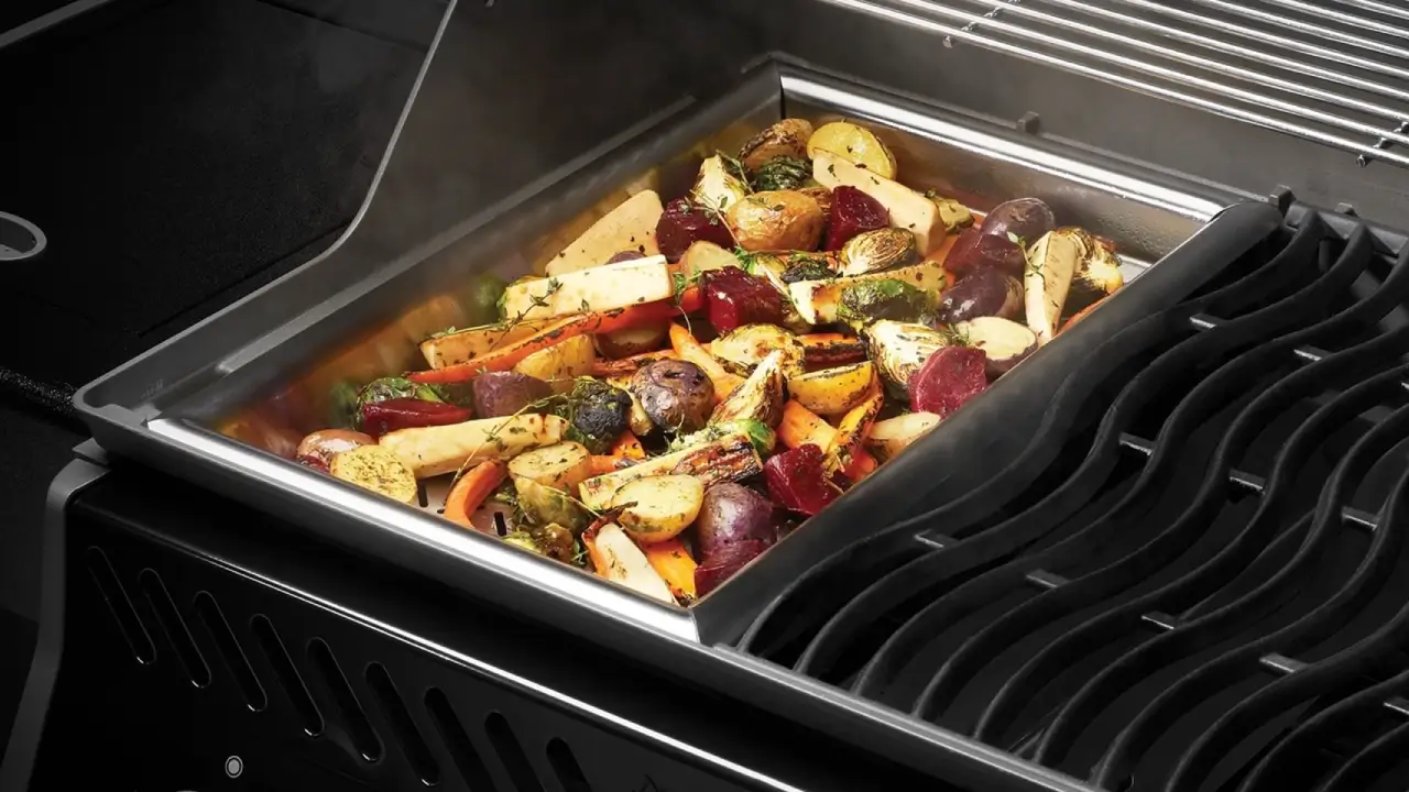 Grillbakke fyldt med grillede rodfrugter, kartofler og krydderurter klar til servering.